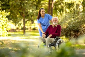 A senior resident arranging family photos on a bedside table in a well-lit assisted living room.